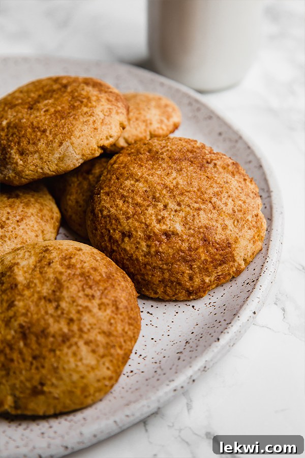 A beautifully arranged white ceramic plate showcasing a stack of golden-brown pumpkin snickerdoodle cookies.