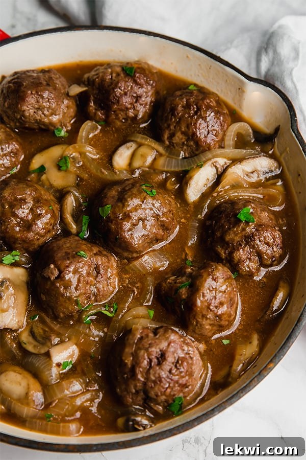 Salisbury steak meatballs simmering in a rich mushroom gravy in a large skillet, ready to be served.