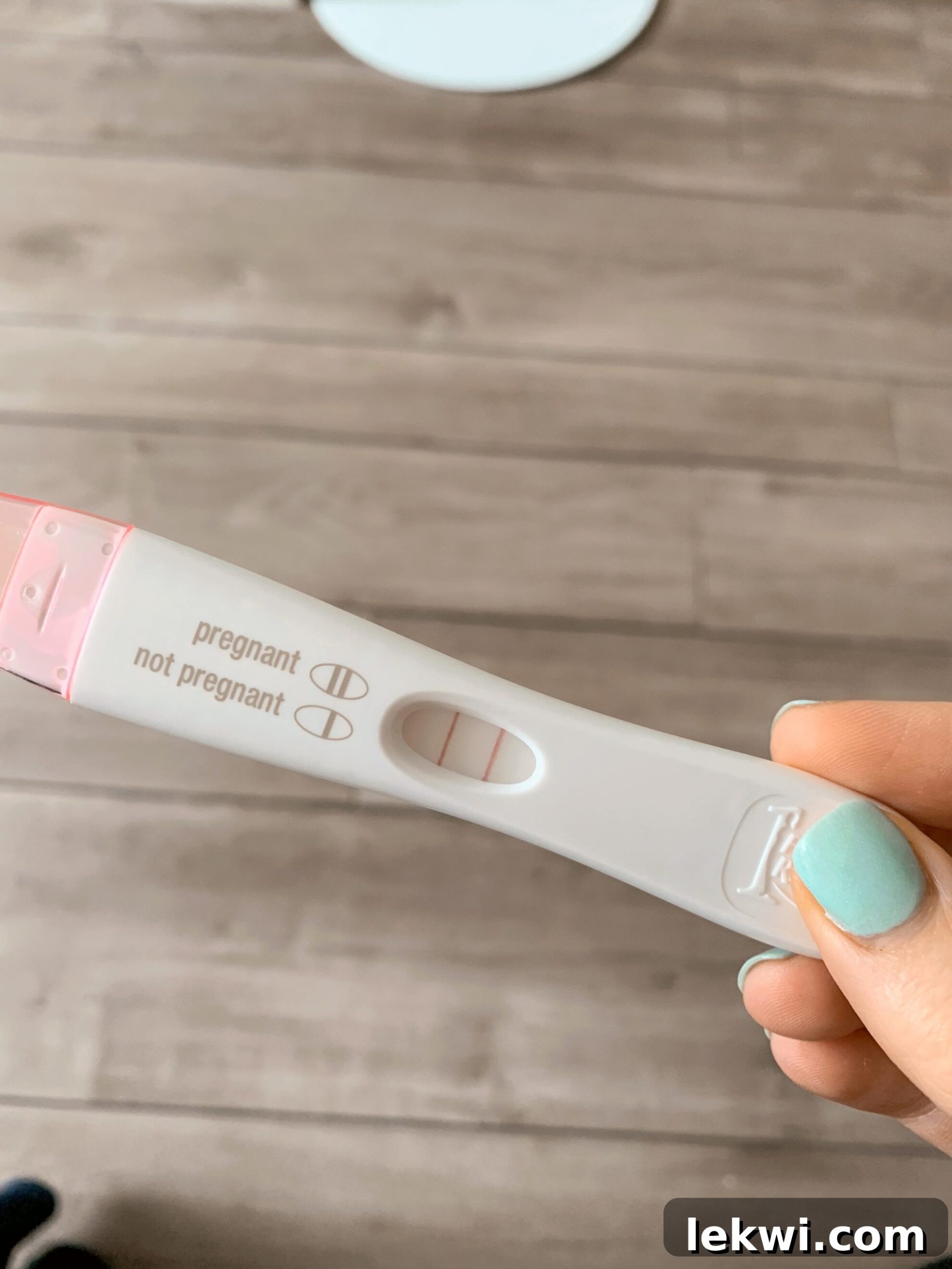 A hand holding a pregnancy test with two lines on it indicating it is positive.