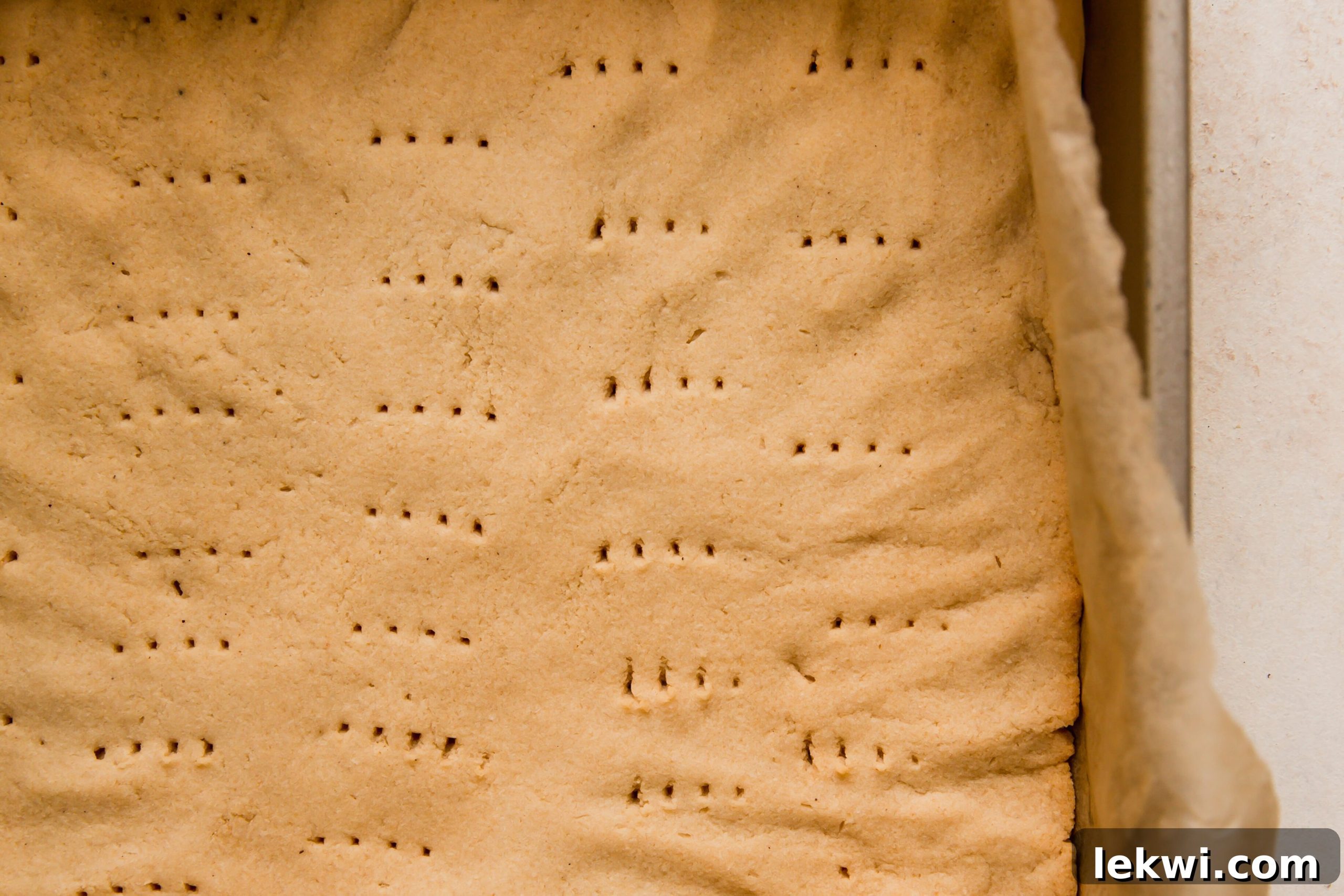 Unbaked shortbread crust flattened in a baking pan.