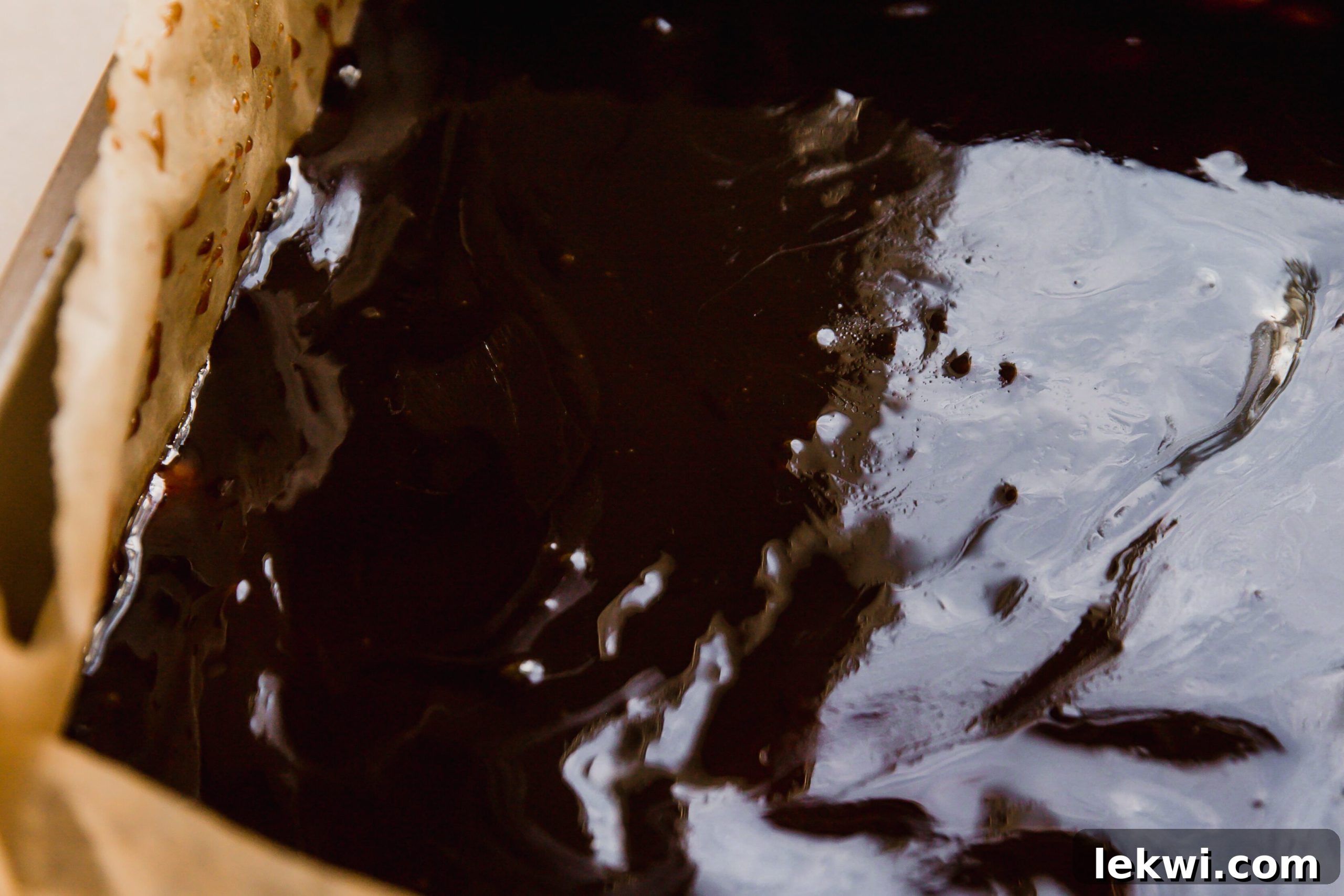 Shortbread crust topped with caramel in a baking pan, ready for chocolate.