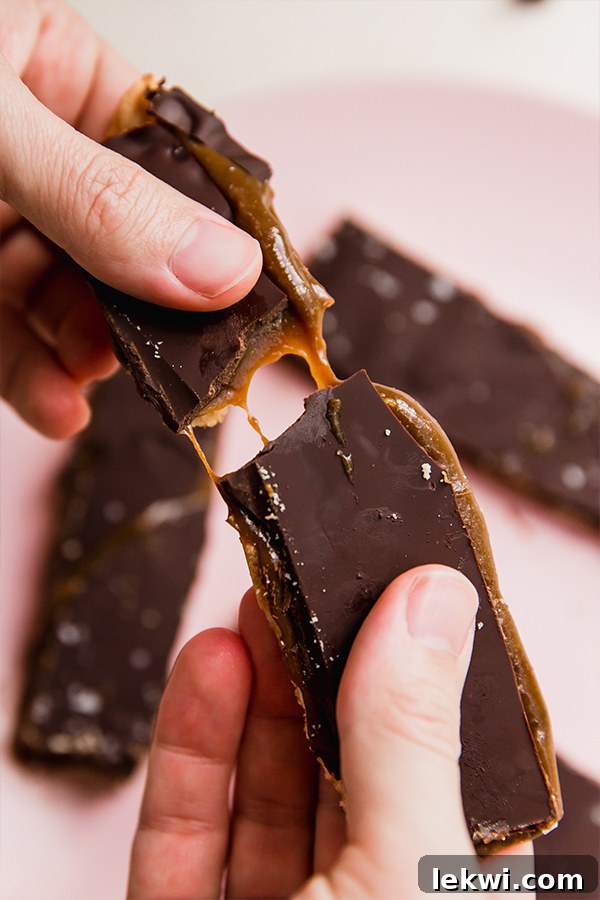 Person breaking a gluten-free Twix bar, showcasing its layers.