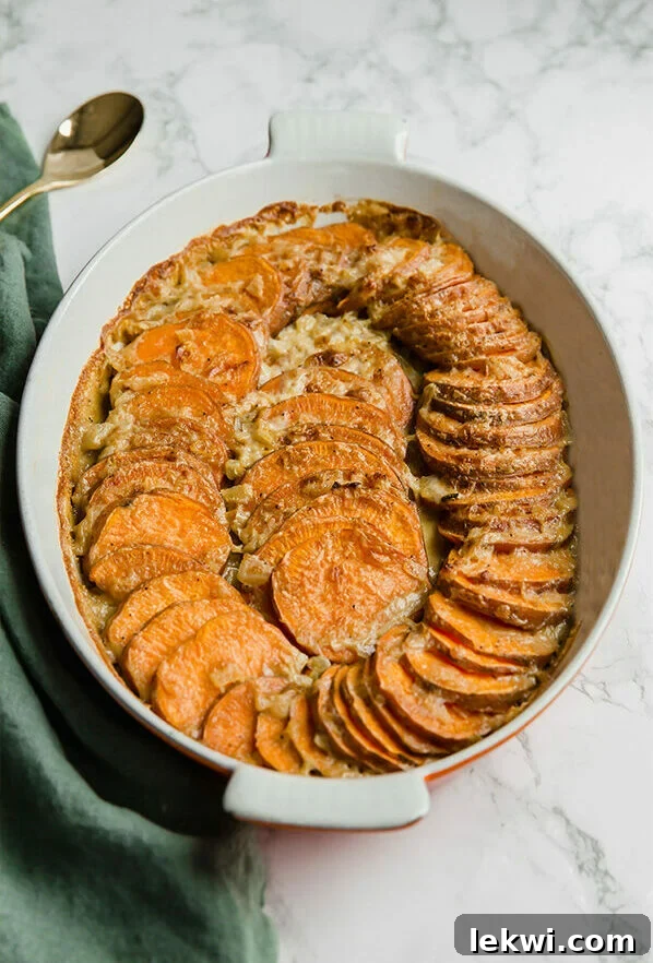 A white bowl filled with healthy sweet potato gratin, garnished with fresh herbs.
