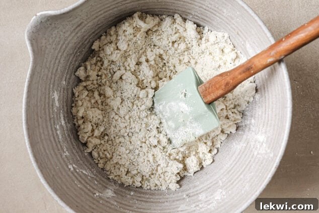 Dry ingredients in a bowl after palm shortening, olive oil, and apple cider vinegar have been added, showing a crumbly texture.