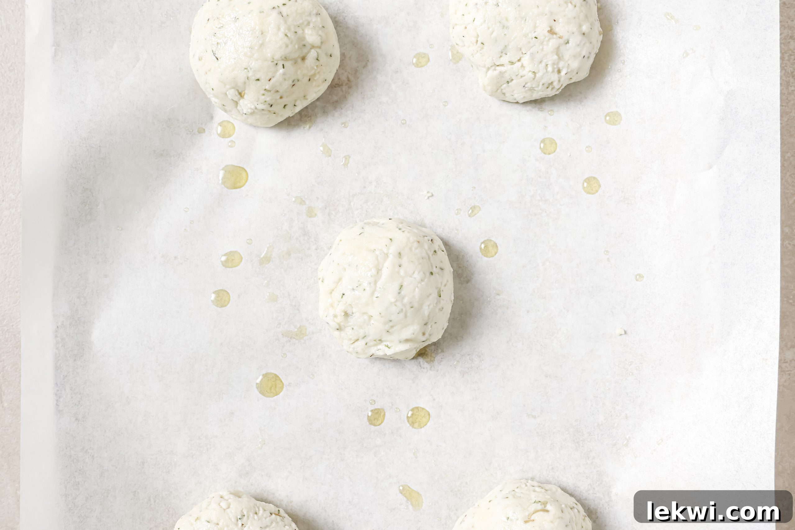 Five uncooked, round AIP bread rolls placed neatly on a baking sheet, ready for the oven.