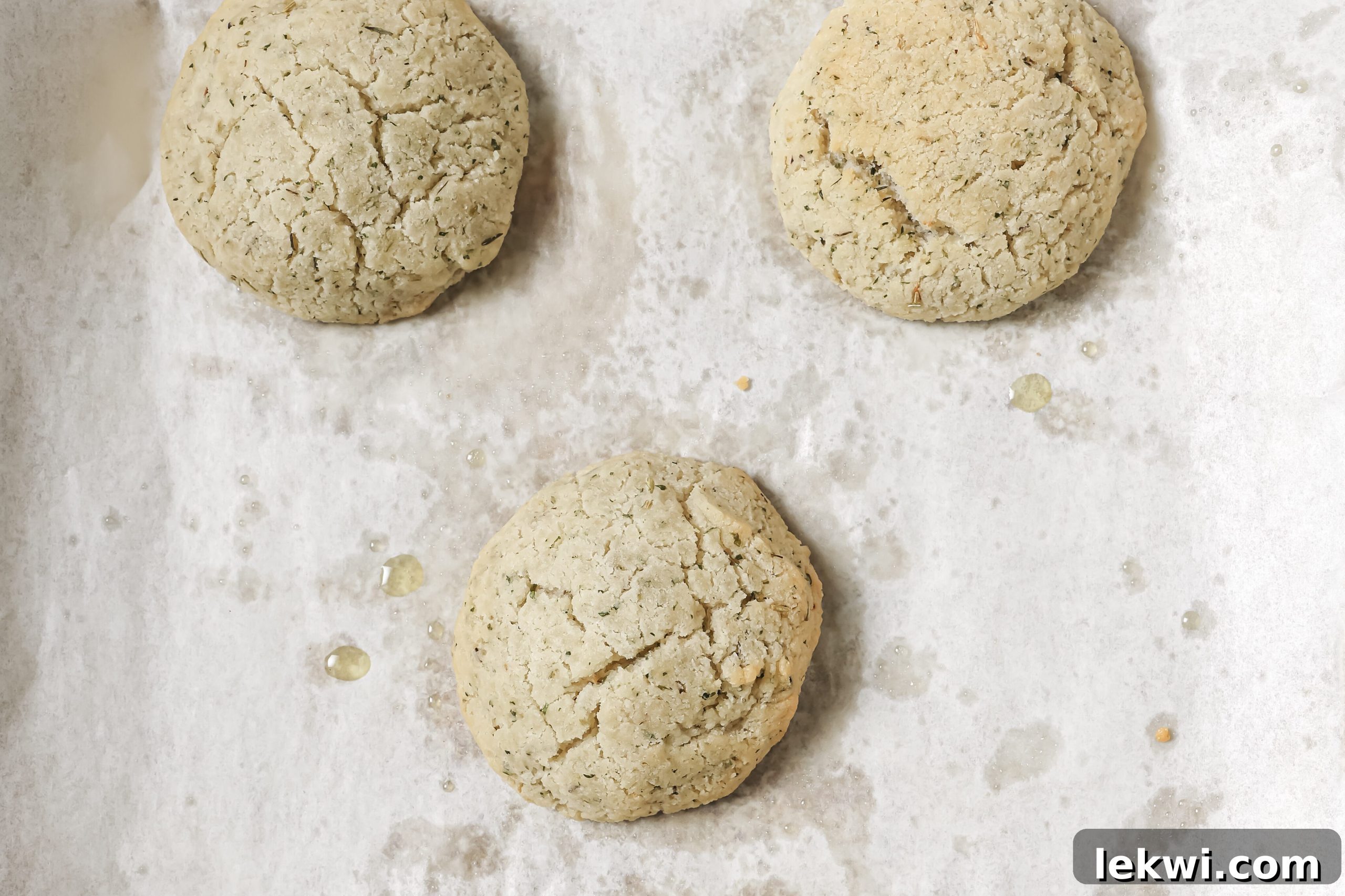 Five perfectly golden-brown, cooked AIP bread rolls on a baking sheet, fresh out of the oven.