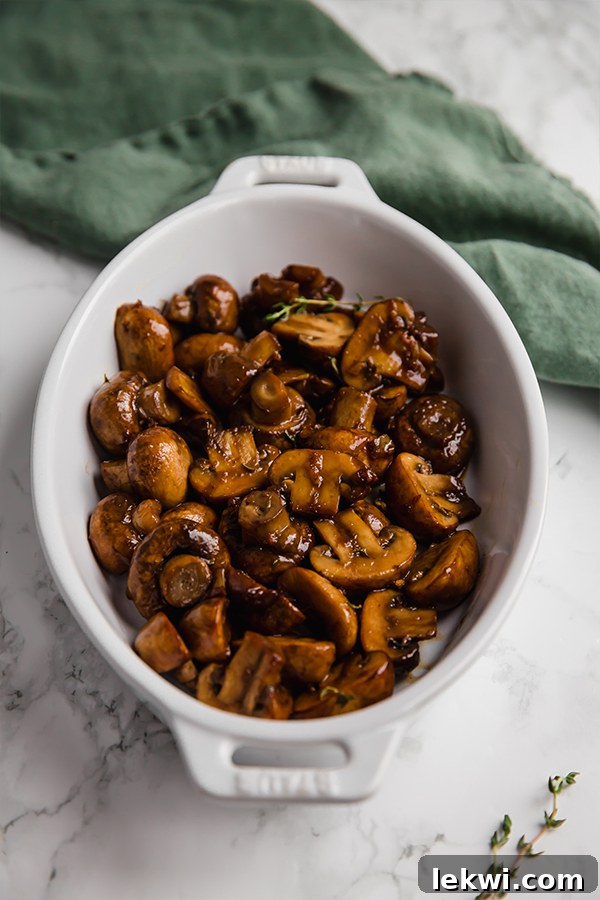 Close-up of freshly cooked garlic balsamic mushrooms in a white bowl, ready to serve.