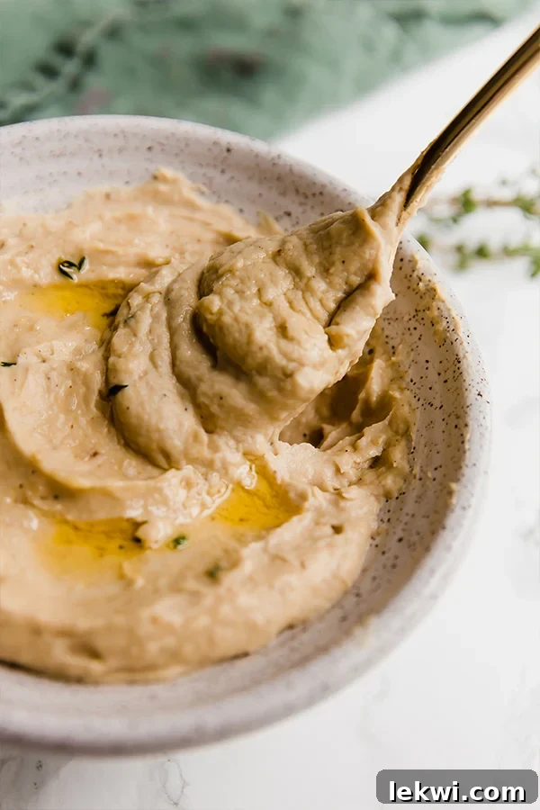 A bowl of roasted cauliflower and parsnip mash with a spoon resting in it, ready to be enjoyed.