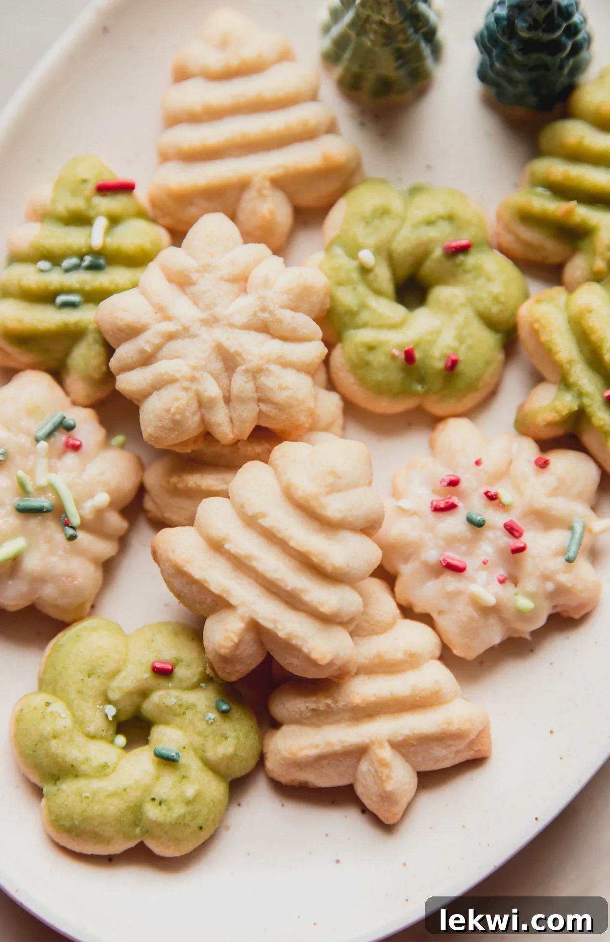 Spritz cookies in festive shapes topped off with sprinkles on a platter.