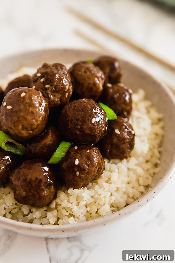 Close-up of Mongolian Meatballs served over a bed of fluffy cauliflower rice, garnished with green onions, highlighting a healthy, gluten-free, and delicious meal option.