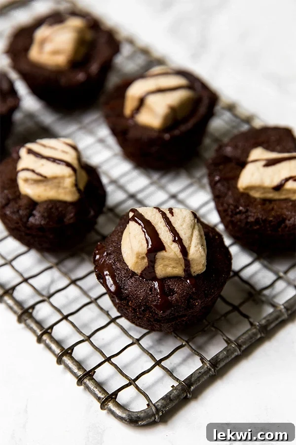 A cooling wire rack showcases a batch of freshly baked hot chocolate cookie cups, ready for their festive holiday topping.