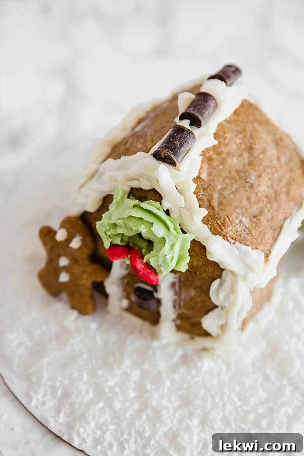 A beautifully crafted homemade gingerbread house stands proudly with a charming gingerbread man leaning against its side, evoking classic holiday cheer.