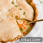 A chicken pot pie with a slice taken out of it and a spoon in it.
