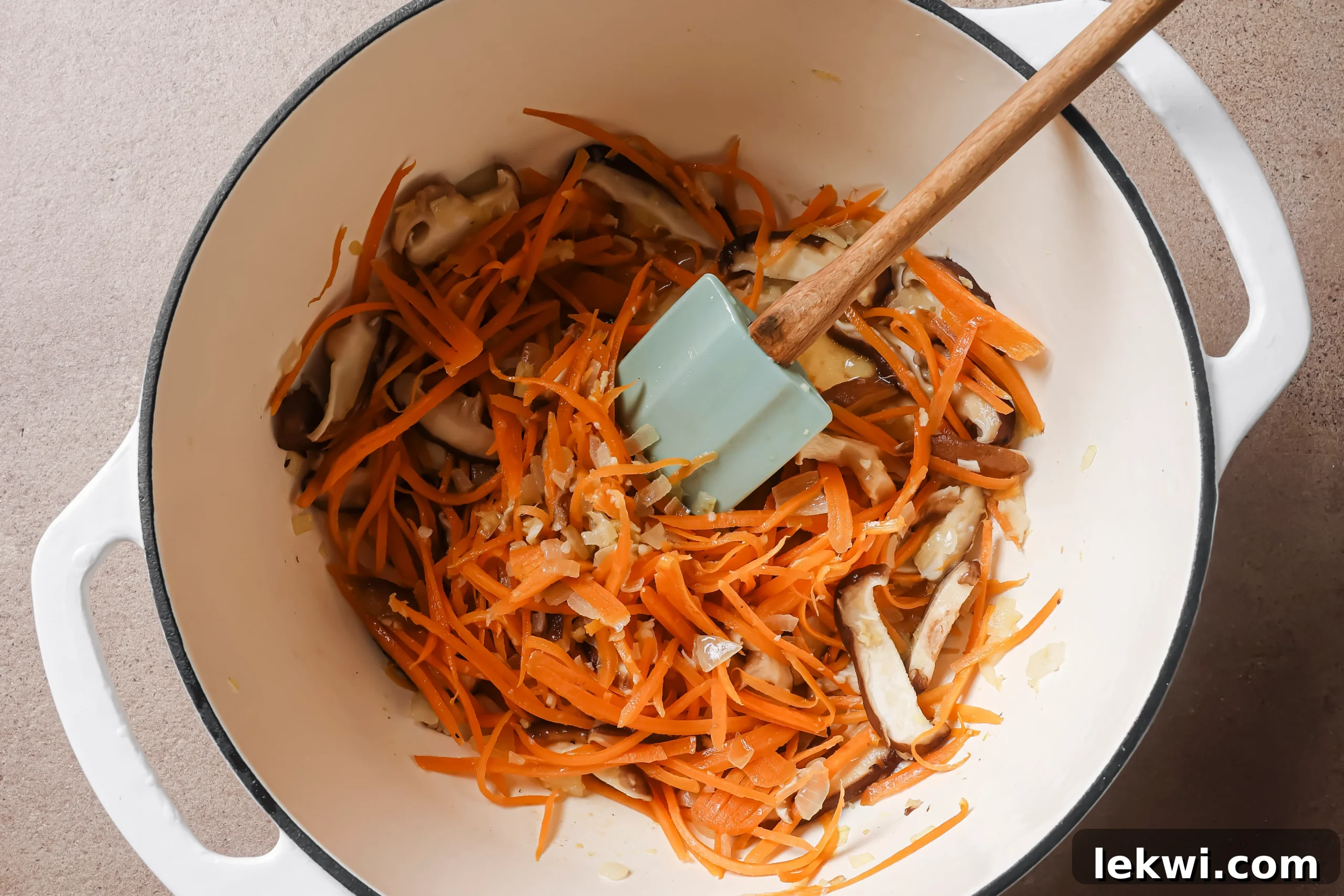 Onion, carrots and mushrooms sautéing in a pot.