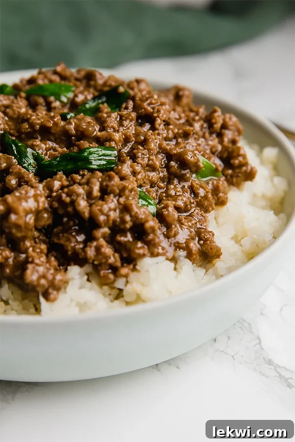 A white bowl filled with cauliflower rice topped with Mongolian ground beef.