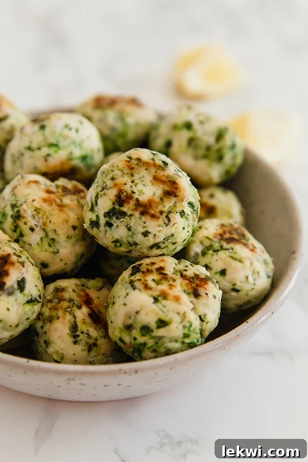A beautifully arranged bowl filled with golden-brown Mediterranean veggie and chicken meatballs, garnished with fresh herbs, showcasing their healthy and appealing texture.
