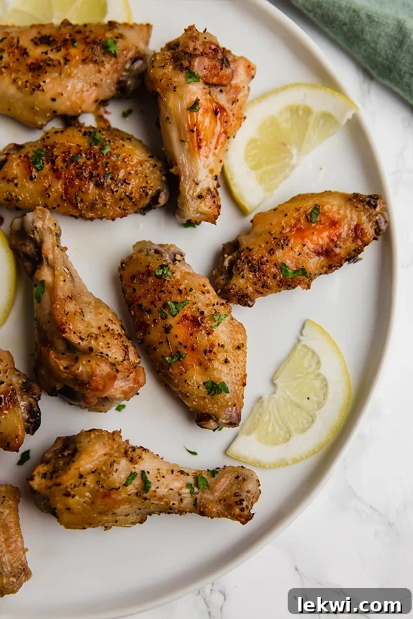 A tantalizing plate of golden-brown lemon pepper chicken wings, garnished with fresh parsley and lemon slices.
