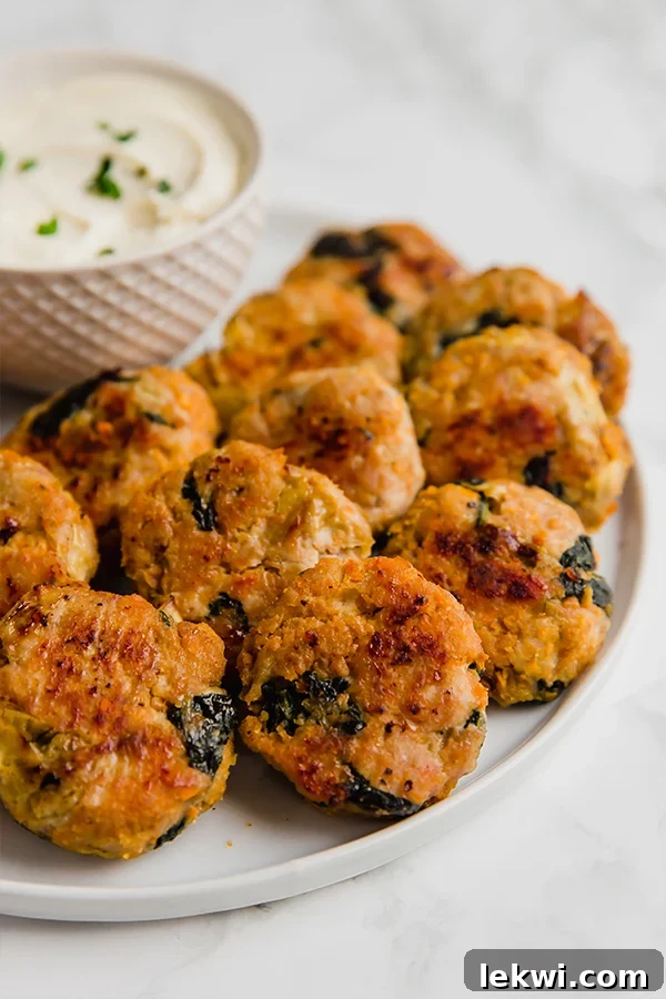 A white plate filled with perfectly golden spinach and artichoke sweet potato chicken poppers, ready to be served.