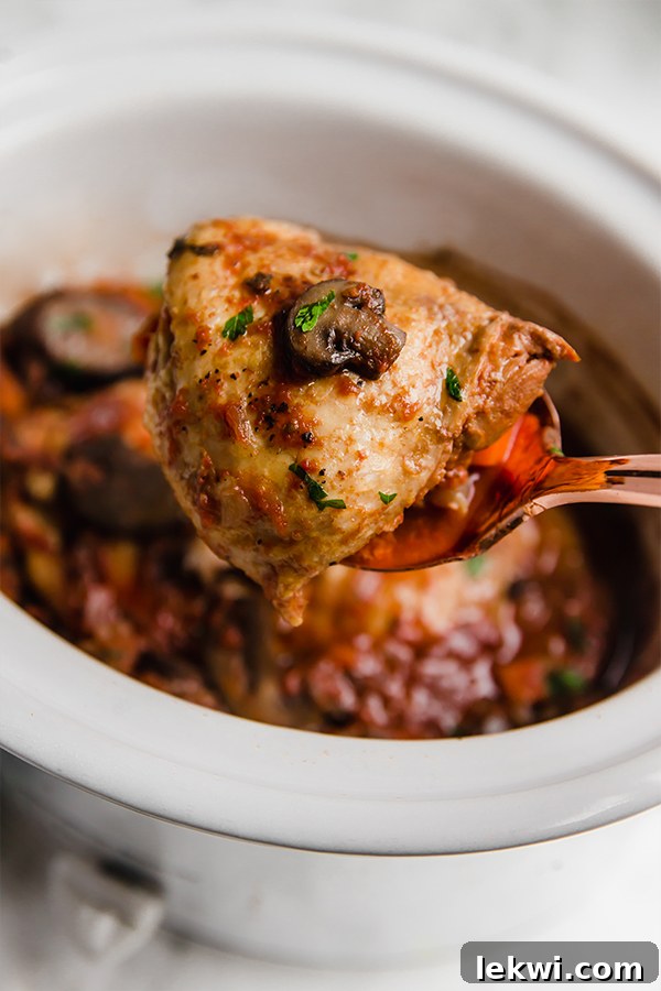A spoon taking a pieces of slow cooker chicken cacciatore out of a slow cooker.