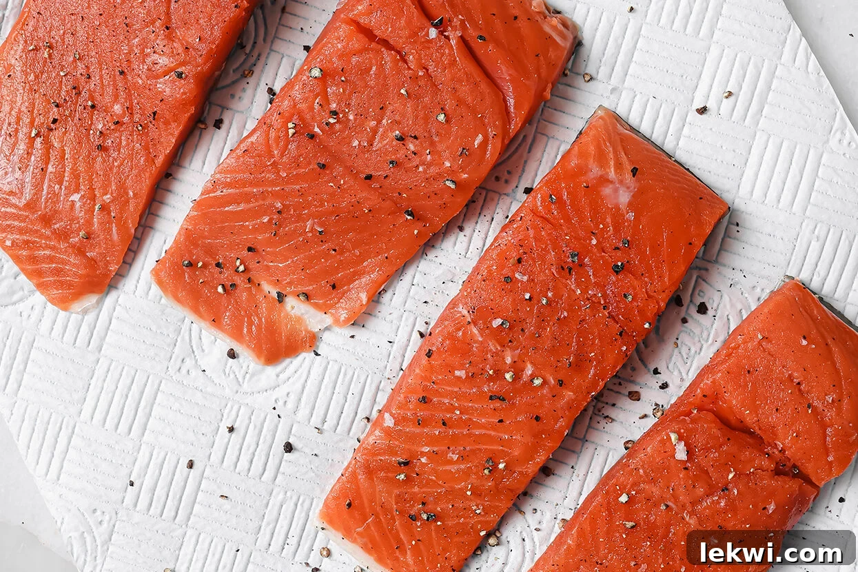Seasoned salmon fillets, raw on a paper towel, prepared for cooking.