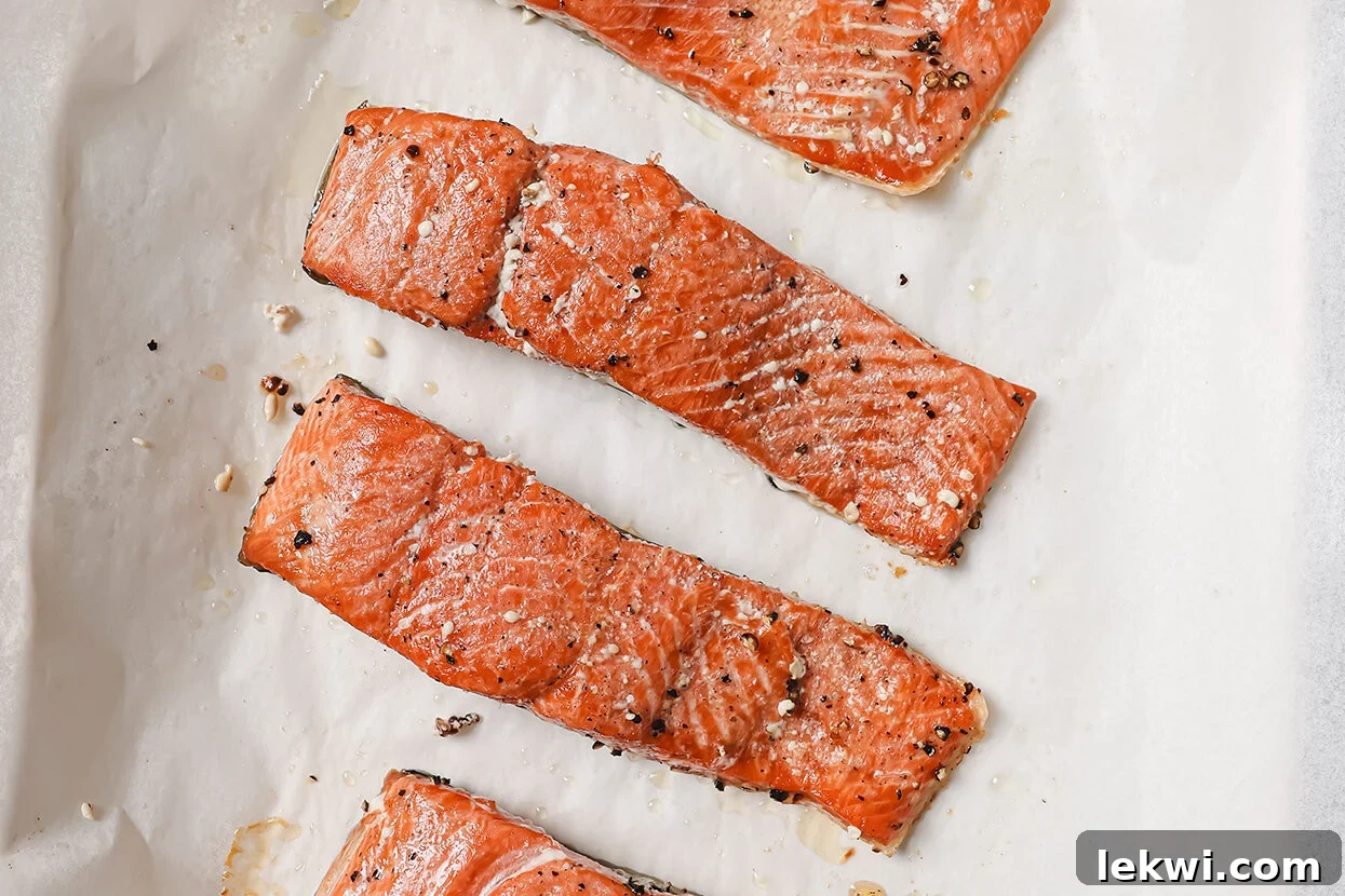 Perfectly cooked salmon fillets on parchment paper, ready to be added back to the sauce.