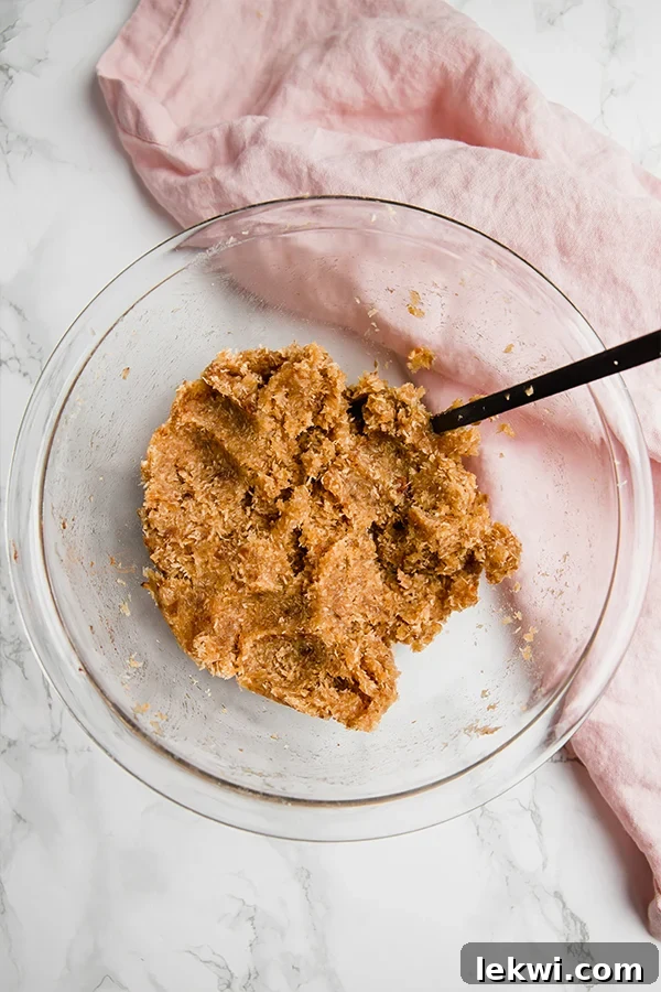 A bowl filled with the date and shredded coconut truffle mixture, ready to be rolled into balls.