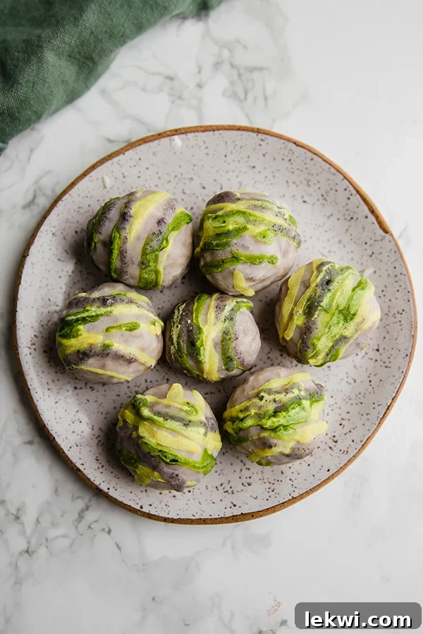Close-up of three no-bake king cake truffles on a white plate, showcasing their colorful drizzles.