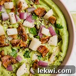 A pink bowl filled with apple bacon guacamole.