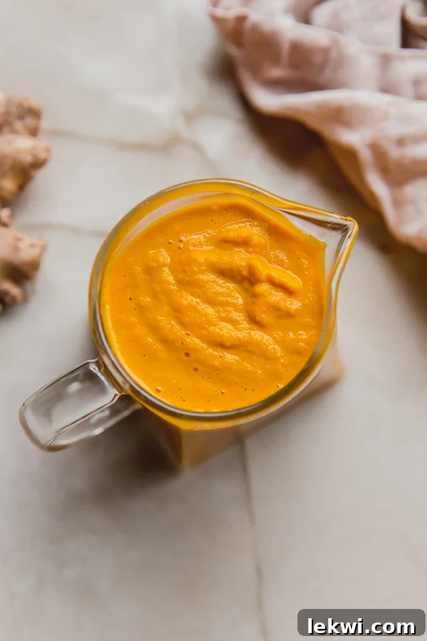Bright ginger dressing in a small pitcher.