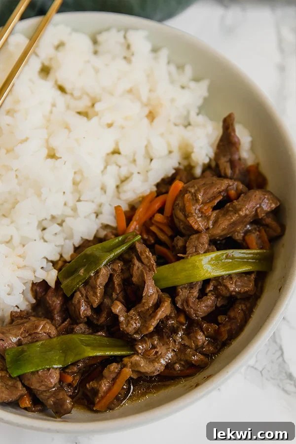 A white bowl filled with cauliflower rice and mongolian beef.