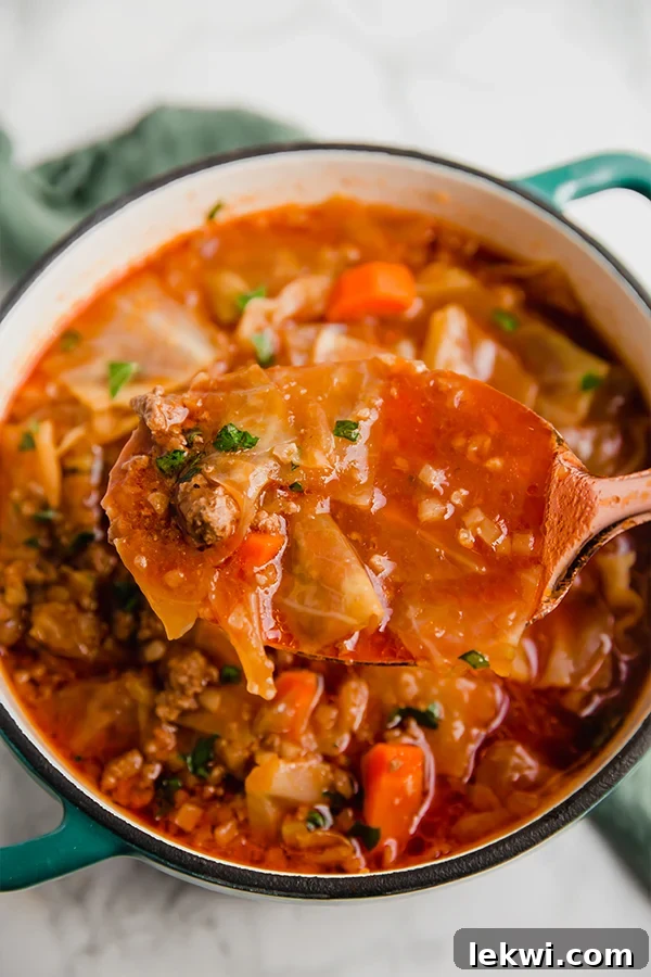 Close-up shot of a steaming bowl of homemade cabbage roll soup, showing tender pieces of cabbage, ground beef, and colorful vegetables in a rich tomato-based broth, ready to be enjoyed as a hearty meal.