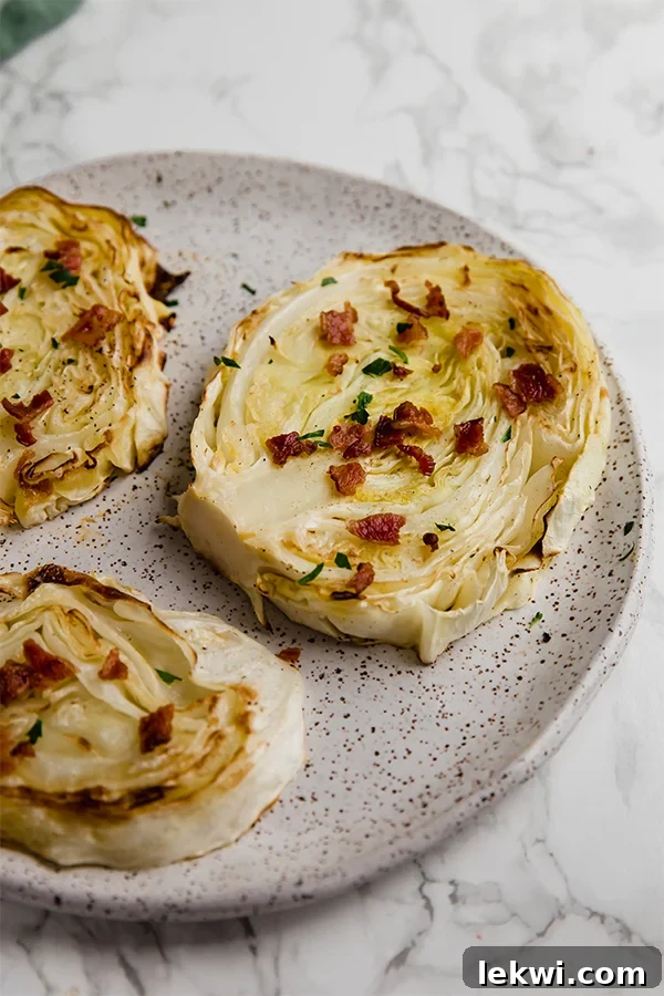 A speckled plate filled with oven roasted cabbage steaks, garnished with fresh herbs.