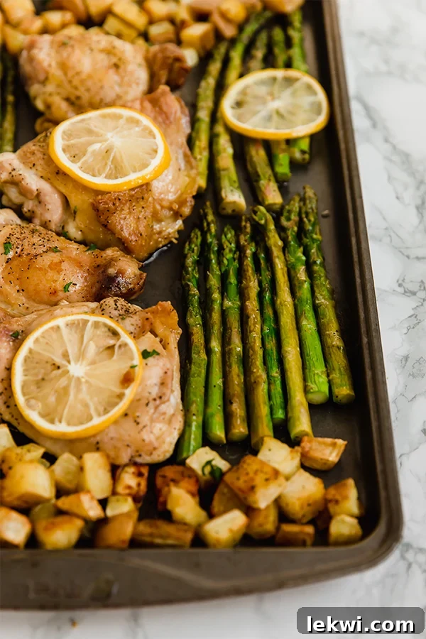 A vibrant sheet pan with lemon chicken, roasted asparagus, and sweet potatoes, freshly pulled from the oven.