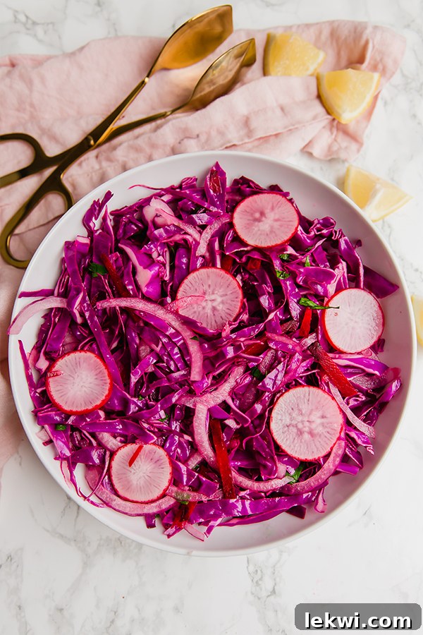 A bowl of purple coleslaw with a fork, ready to be served, highlighting its freshness.