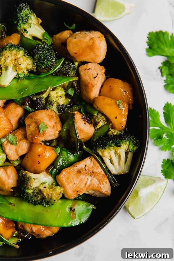 A close-up shot of the finished mango chicken stir fry, garnished with fresh cilantro, ready to be served.