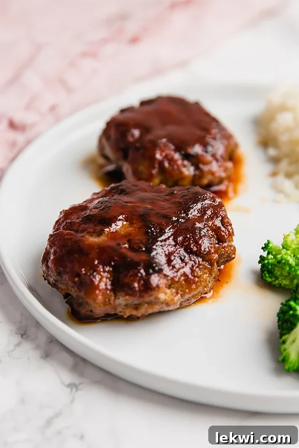 A white plate topped with Japanese hamburger steaks, garnished with fresh broccoli florets.