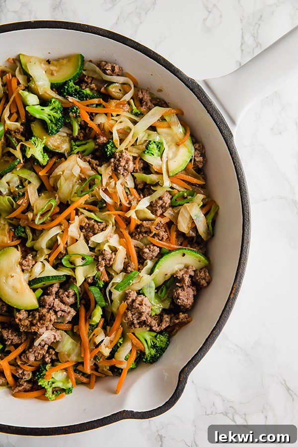 A close-up view of ground beef and cabbage stir fry in a large pan.