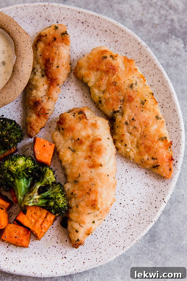 Crispy chicken tenders served on a plate with a side of roasted vegetables.