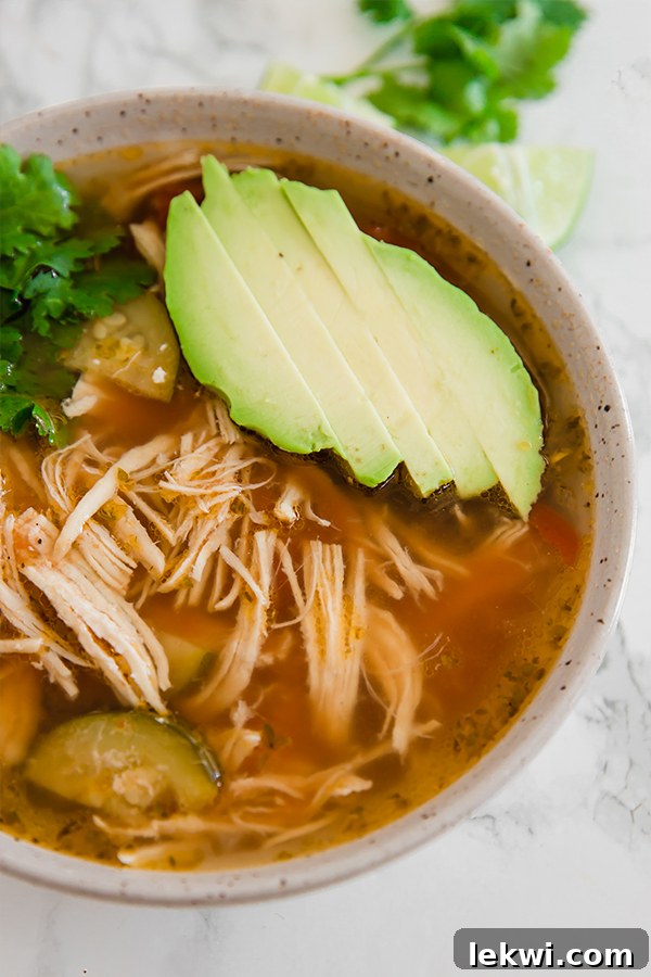 A bowl of chicken tortilla soup topped with fresh avocado slices.