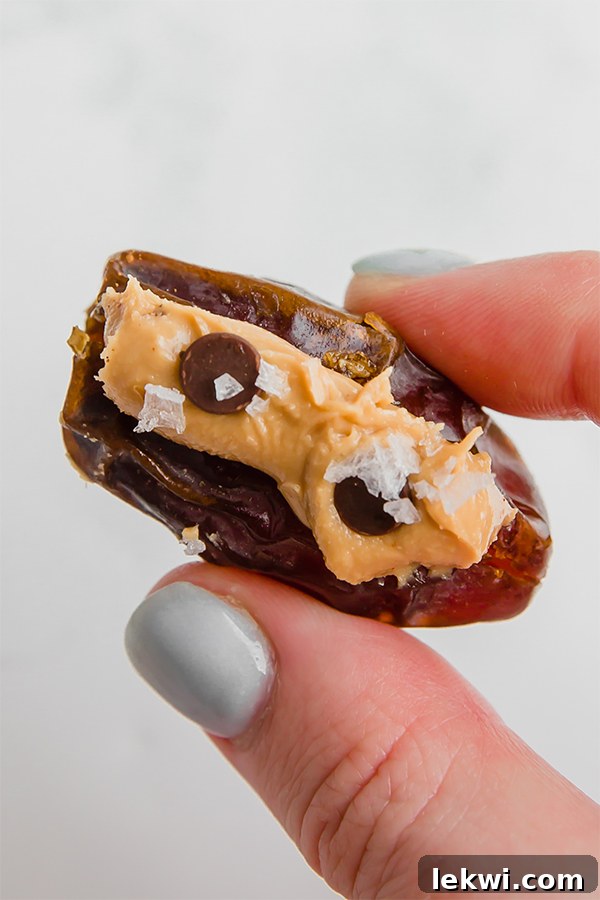 A hand holding an almond butter stuffed date in it.