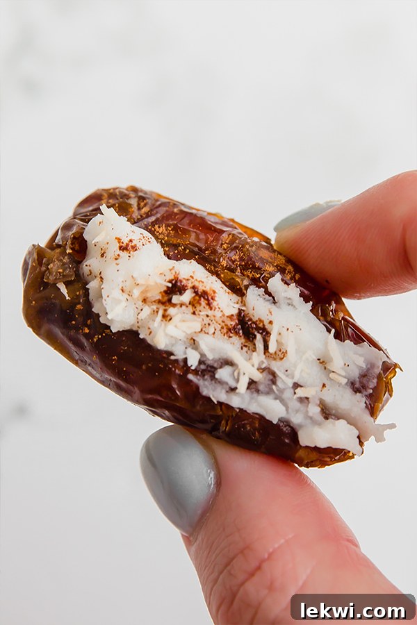 A hand holding an coconut butter stuffed date in it.