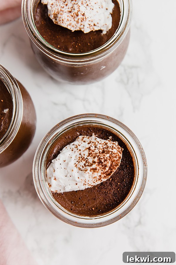 A few glass jars filled with homemade chocolate pudding, garnished with fresh berries.