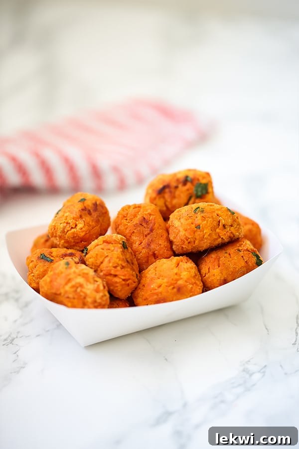 A white paper container filled with sweet potato tater tots.