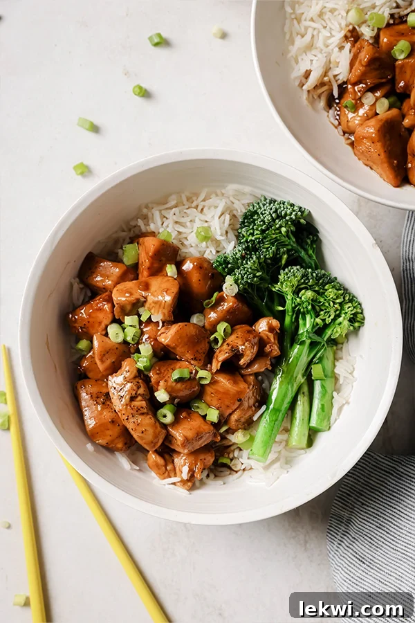 Delicious and healthy bourbon chicken served with fluffy rice and vibrant broccolini in a modern white bowl, ready to be enjoyed.