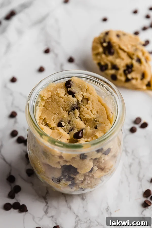 Close-up of a bowl filled with rich, decadent edible cookie dough, garnished with chocolate chips.