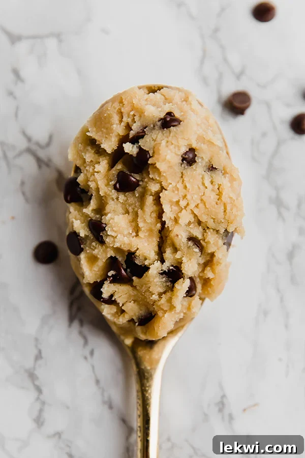 A large spoon with edible cookie dough on it, showcasing its delicious texture.