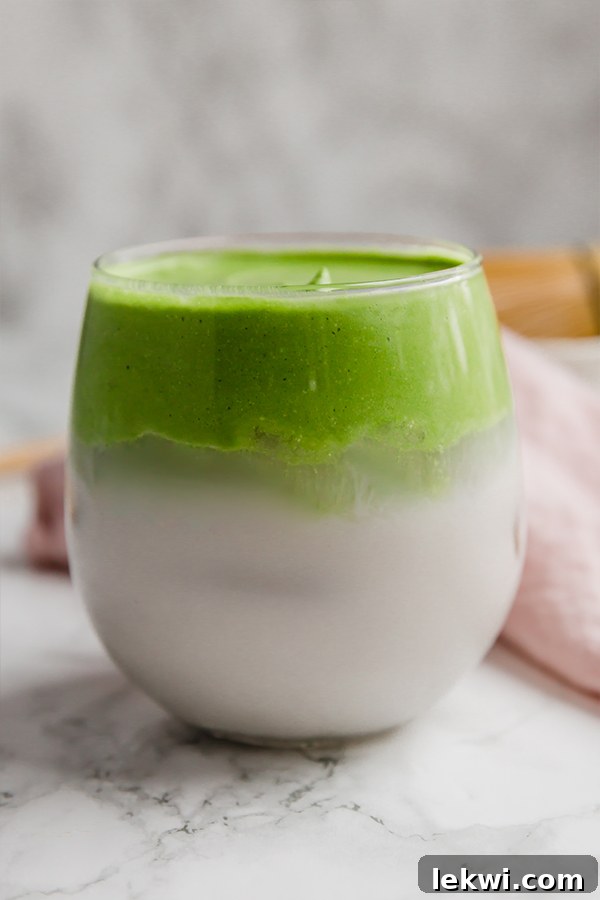 A glass filled with dalgona matcha, beautifully layered, ready to be enjoyed.