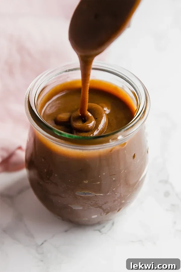 Homemade Paleo Dulce de Leche in a jar with a spoon, highlighting its creamy texture