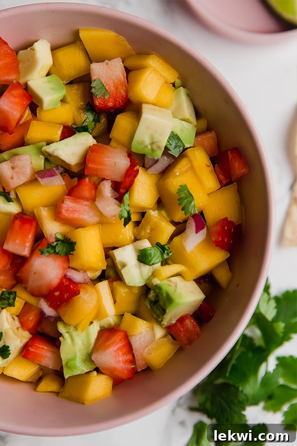 A close-up shot of a bowl of freshly made strawberry mango salsa, highlighting the vibrant colors and fresh fruit pieces.