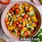 A pink bowl filled with strawberry mango salsa.